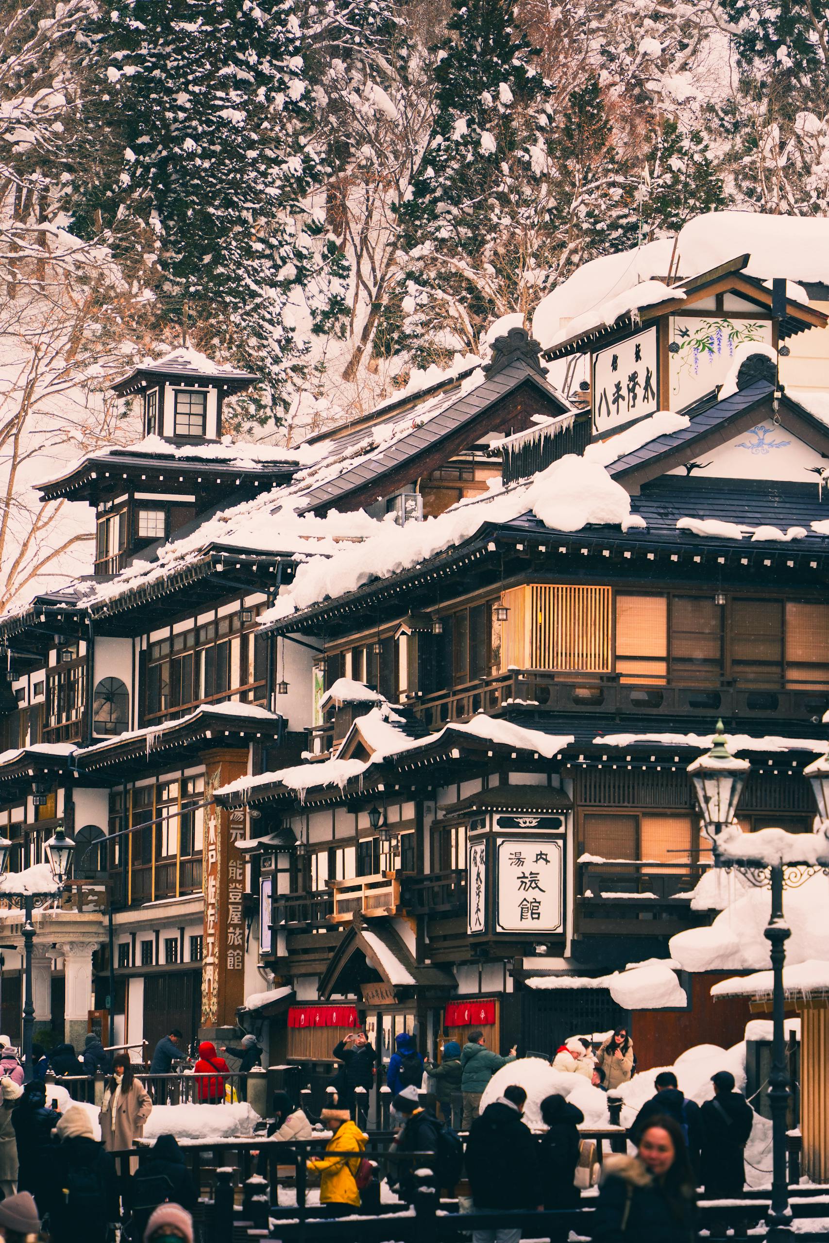 A scenic view of a traditional Japanese onsen surrounded by snow-covered trees, capturing seasonal beauty.