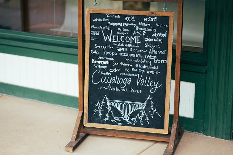 Chalkboard sign welcoming visitors to Cuyahoga Valley National Park in various languages.