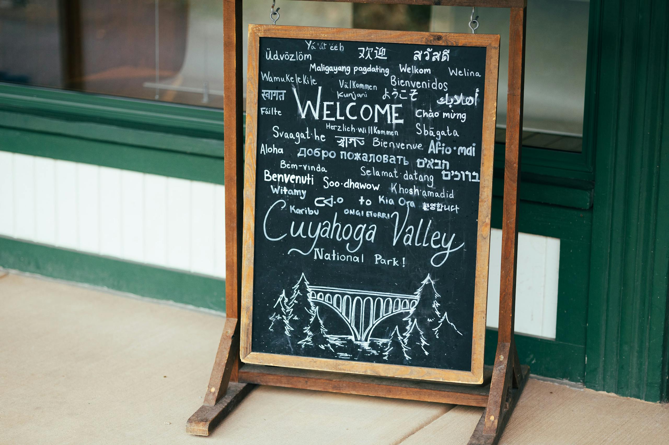 Chalkboard sign welcoming visitors to Cuyahoga Valley National Park in various languages.